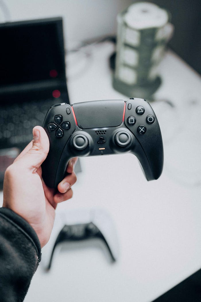A close-up view of a black PlayStation 5 controller held by a man, highlighting its sleek design and technology features.